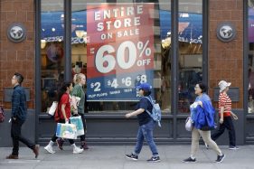 In this July 3, 2018, photo, shoppers walk past sale signs in San Francisco
